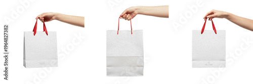 Quadro su tela Set of hands holding a white paper shopping bag with red handles, mockup concept for retail branding, fashion boutique, and gift delivery on a white background
