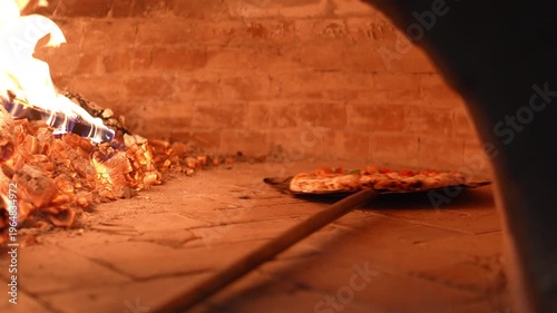 4K Pizza baking inside a wood-fired oven with visible flames and crispy crust Traditional Italian cooking, Concept ideal for restaurant food.