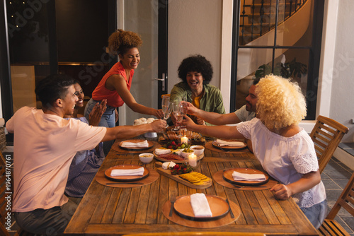 Host starting toast, group raising wine glasses and clinking over cheese board, celebrating food