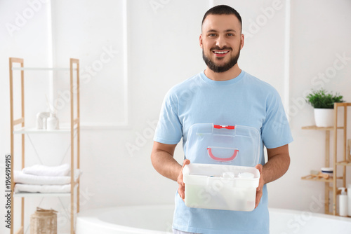 Young man with first aid kit in bathroom