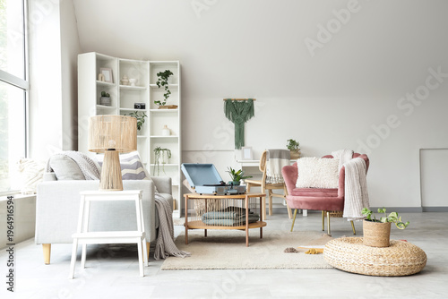 Interior of light living room with record player, sofa and armchair