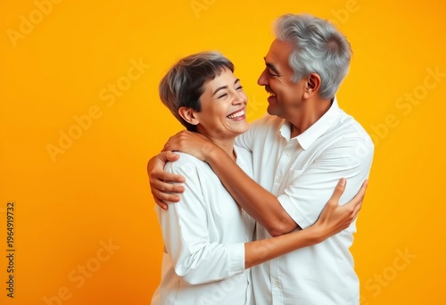 Loving embrace between an older figure and a young one in white shirts on a bright yellow-orange studio background, symbolizing family joy,  care,  tenderness