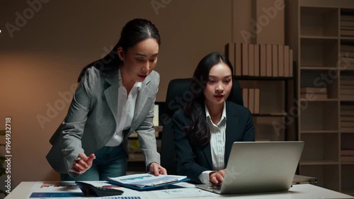 Two businesswomen colleagues discussing project working late at night