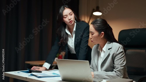 Two asian businesswomen collaborating overtime on a project in the office