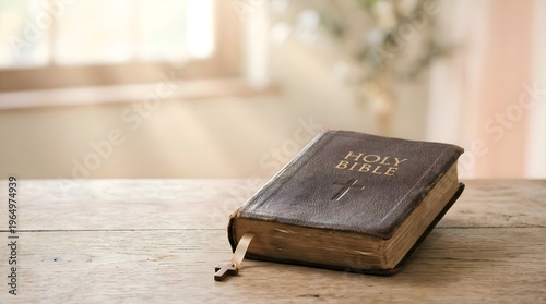Old Holy Bible on a rustic wooden table with natural light from a window.