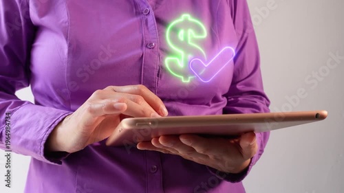 Payment confirmed. Close-up of a businesswoman interacting with her tablet, using a virtual dollar sign icon with a checkmark.