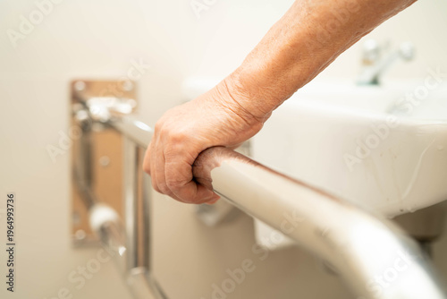 Asian elderly woman use safety handrail in bathroom.