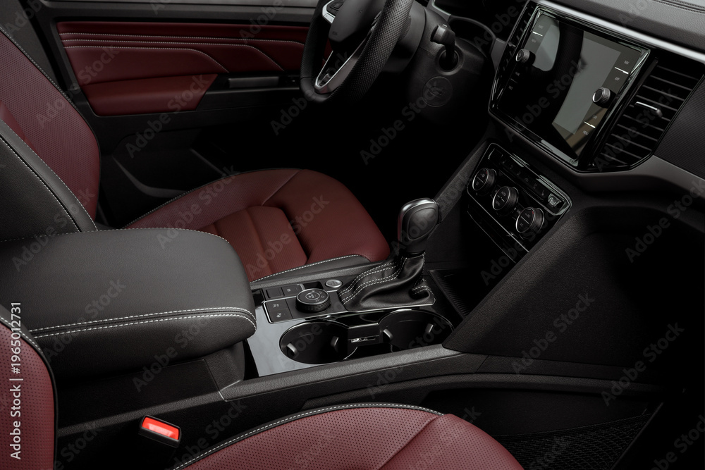 Obraz premium side view of the interior of a luxurious car dashboard, red leather seats, automatic transmission, steering wheel and touch screen