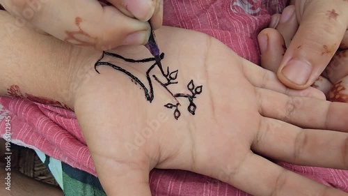 Henna design being created on a hand with intricate patterns and artistic details in black ink