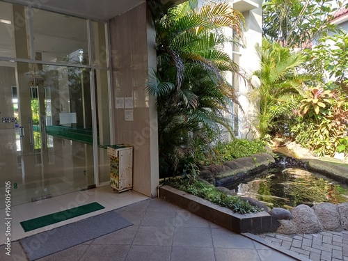 Fotografía A peaceful Mosque features a decorative fishpond surrounded by tropical plants and green palm trees