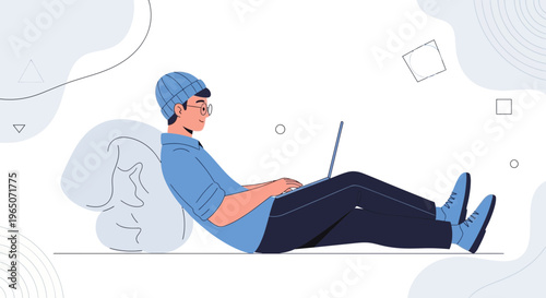 Young man in beanie and glasses working on laptop, relaxing on beanbag chair