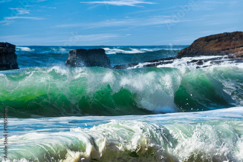 Powerful ocean waves crashing under a clear blue sky. Dynamic seascape with rolling surf, sea foam and energy of moving water, capturing the raw force and beauty of nature in motion
