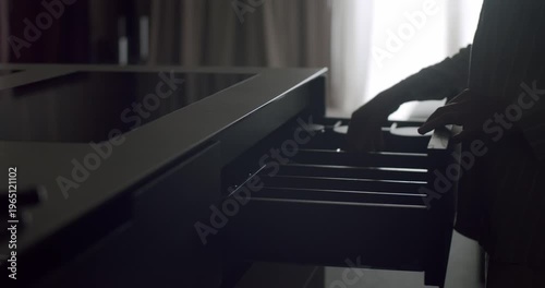 Moody and mysterious silhouette of a person holding a knife over open drawers in a dimly lit kitchen. Silhouette of a Person Holding Knife Over Drawers in a Dimly Lit Kitchen