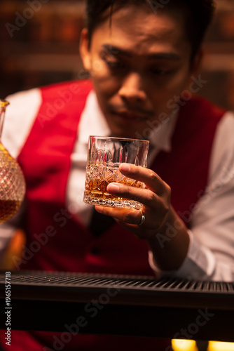 Bartender Holding a Glass of Premium Whiskey on Bar Counter