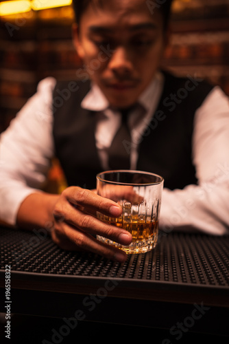 Bartender Holding a Glass of Premium Whiskey on Bar Counter