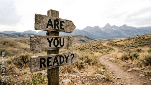 Wooden signpost in a mountainous landscape with a winding dirt road