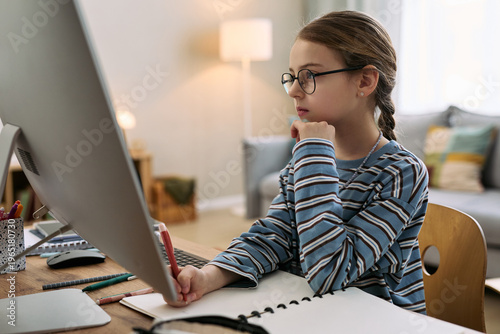 Tableau sur toile Caucasian girl child wearing glasses sitting at desk using desktop computer whil