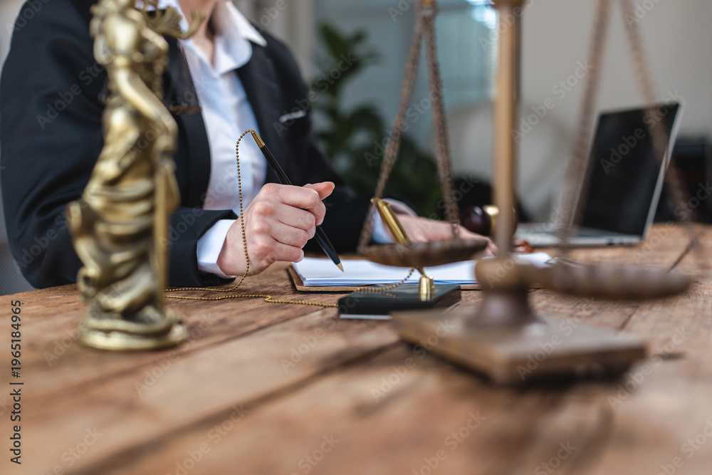 Fototapeta premium Legal professional writing documents with scales of justice