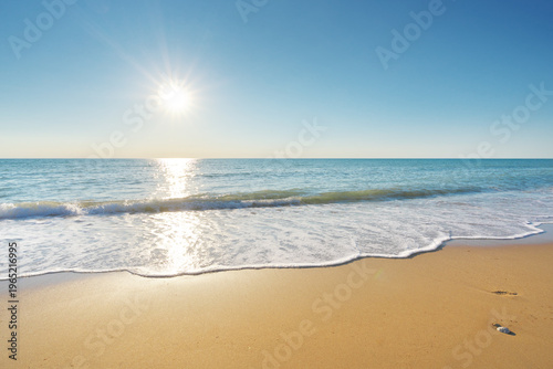 Bright Sun Over Tropical Sandy Beach With Calm Sea Waves And Ocean Horizon.