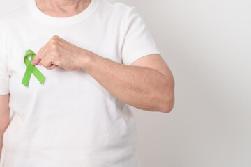 Elderly with light Green Ribbon for concept of May Celiac Awareness month, Lyme disease, September Lymphoma, Mental Health Awareness month and October Liver cancer. Health and world cancer day