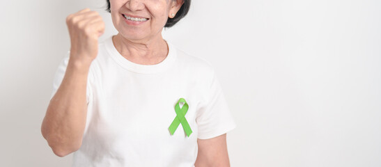 Elderly with light Green Ribbon for concept of May Celiac Awareness month, Lyme disease, September Lymphoma, Mental Health Awareness month and October Liver cancer. Health and world cancer day