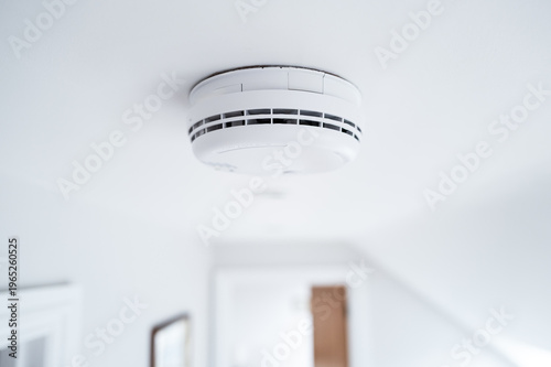 Shallow focus of a newly fitted mains operated smoke alarm detector seen in the upstairs landing of a modern house. One of two detectors, the other downstairs in the hallway.