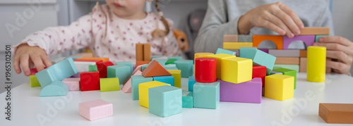 Brother and sister playing with colorful wooden building blocks at home