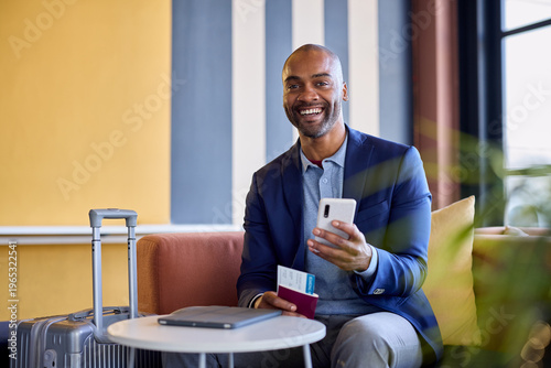 Happy mid adult black business man at airport using smartphone