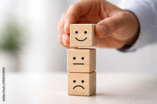 Male Hand Holding Smiling Cube Above Emotion Stack
