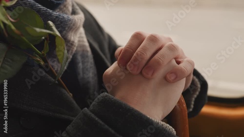 Quiet moment during daily journey. Silent pause captured with clasped palms and thoughtful expression. An individual is holding handle quietly during peaceful afternoon travel reflection