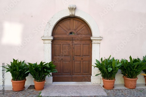 Historic wooden arched doorway with potted green plants