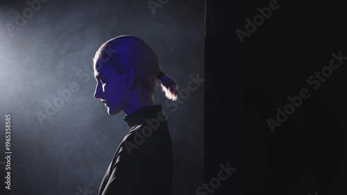 Foto A young blonde woman with a short ponytail steps into a powerful side light