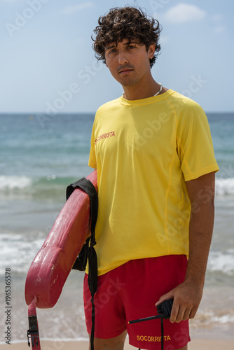 Foto Lifeguard holding rescue board and walkie-talkie on beach