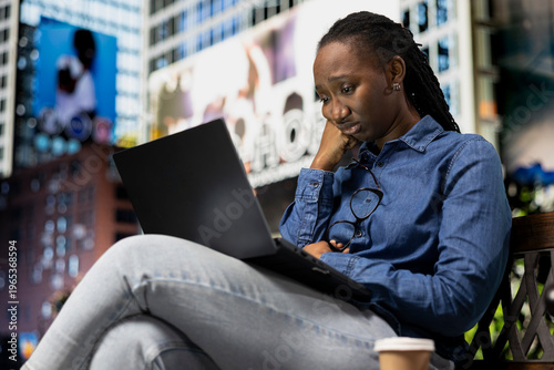 Fotografie Sad woman watching depressing TV show episode on streaming services using laptop on park bench