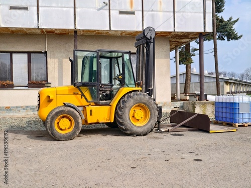 Foto Yellow forklift stands idle outside factory