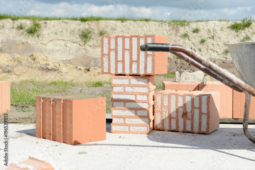 Poroton bricks and wheelbarrow on concrete slab at  construction site