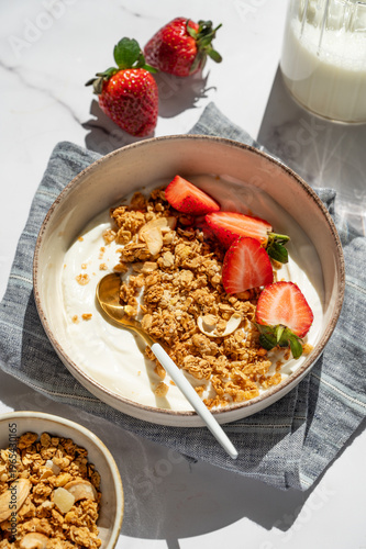 Balanced breakfast with yogurt, granola and strawberry on marble background. Top view