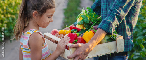 A man farmer and a child are holding vegetables in their hands. Selective focus.