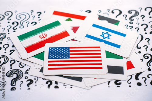 Cards showing United States, Israel, Iran, and Lebanon flags lie on paper covered in question marks. Middle East geopolitical tensions, regional conflict complexity, unstable political landscape.