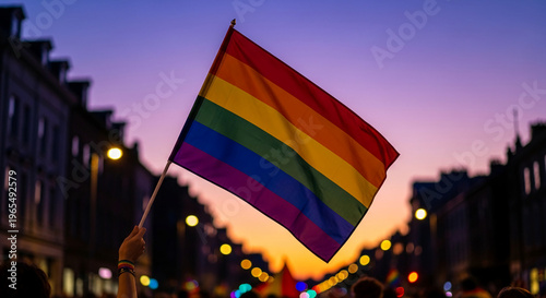 View of waving rainbow flag at dusk, held aloft during parade, representing pride, inclusion, and support for diversity and equality