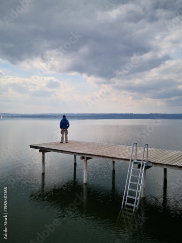 Mann auf Bootssteg schaut aufs Wasser
