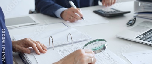Obraz na płótnie Two professional chartered accountants reviewing financial reports and analyzing data using a calculator and a magnifying glass, ensuring accuracy and compliance