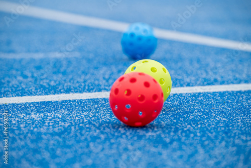 Принти на полотні Red yellow and blue floorball balls on a blue sports court with white lines
