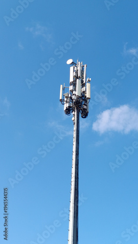 A modern telecommunication cell tower (BTS) with antennas and transmitters against a clear blue sky. Concept of 5G, mobile network, signal coverage, and wireless technology