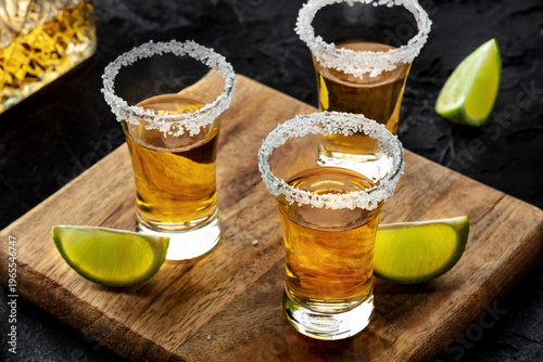 Wallpaper Mural Tequila shots with salted rims and lime slices, with a decanter, on a wooden board on black Torontodigital.ca