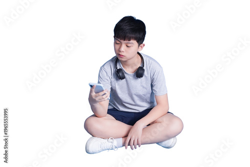 Billede på lærred Boy immersed in smartphone: A young boy, absorbed in his phone, sits cross-legge