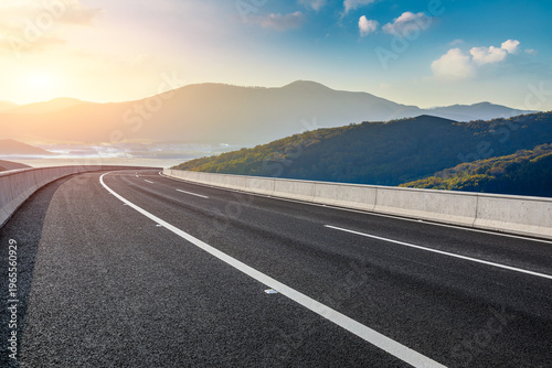 Asphalt highway through mountain landscape under sunset sky