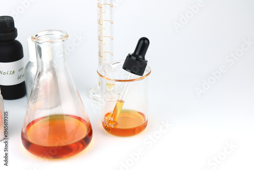 chemical science test tube , beaker or flask used on white table with blotting paper fragrance bottle and essential oil bottle used to blend nice scent for making perfume and candle by perfumer in lab