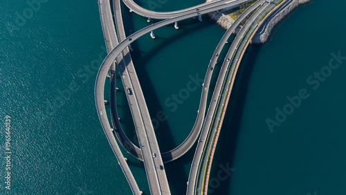 Aerial view of the Cross Bay Link bridge interchange with curved roads over deep blue water in New Territories, Hong Kong.
