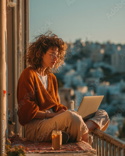 Young professional working on laptop in sunny apartment.